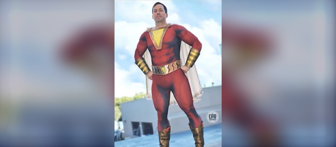 Muscle Base for Dye Sub Suits: How Printed Muscle Shading Creates That Superhero Look 2 Cosplayer in a red Shazam dye sublimation suit with printed muscle shading, shown on a wide banner with a blurred background.